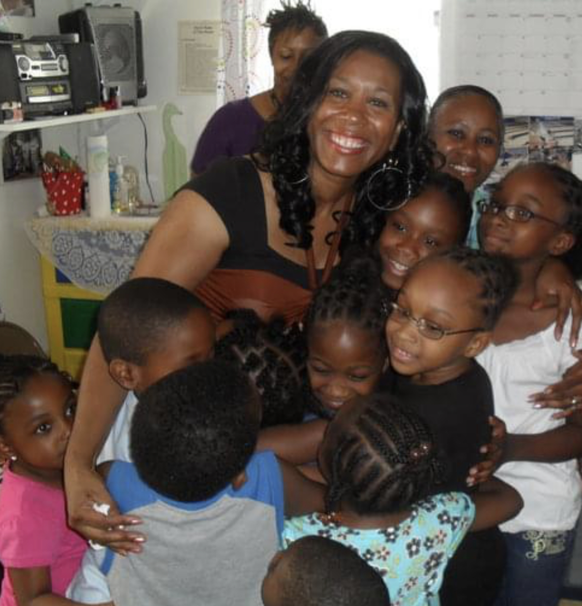 Mary surrounded by children embracing her at a community gathering