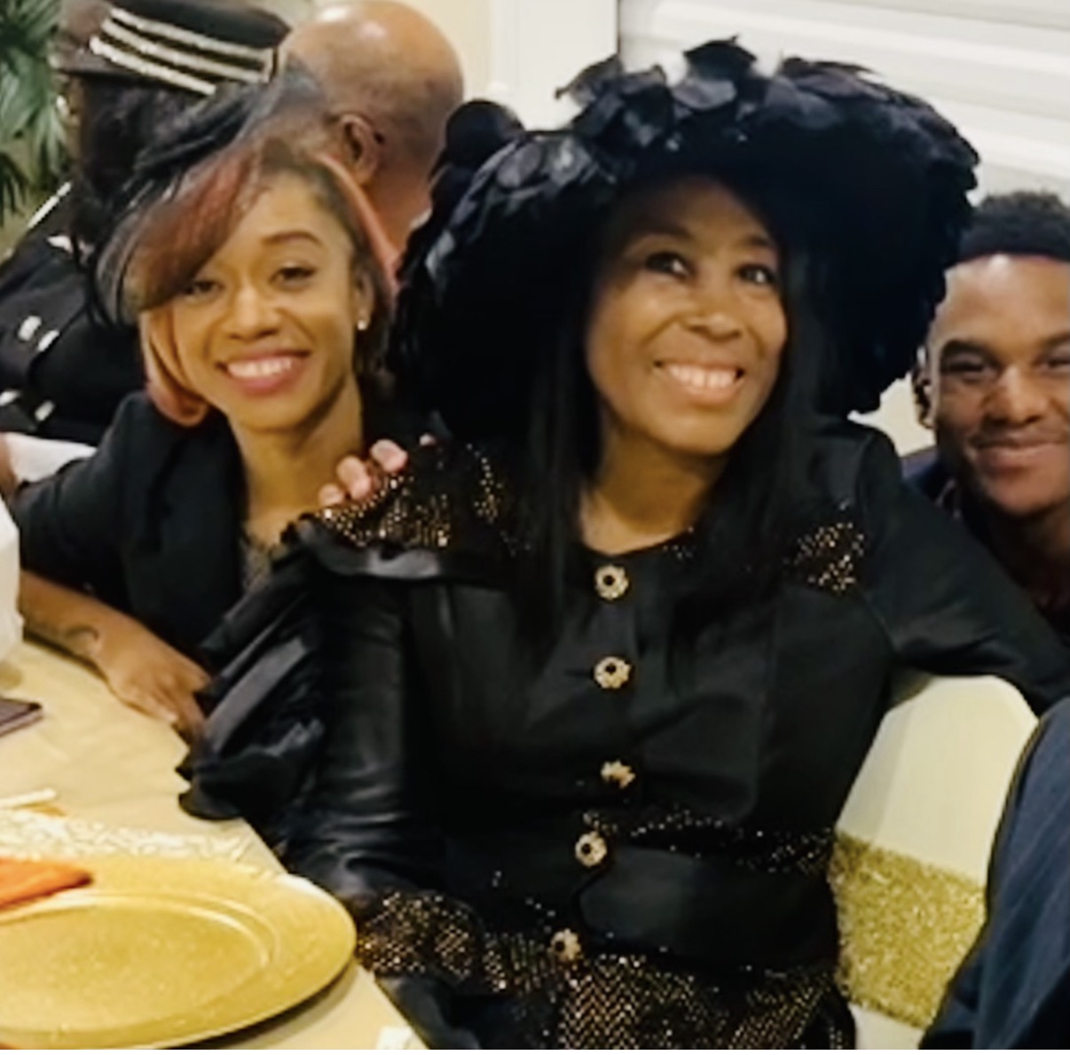 Mary in a dramatic black feathered hat and beaded jacket with her daughter and son at a family gathering
