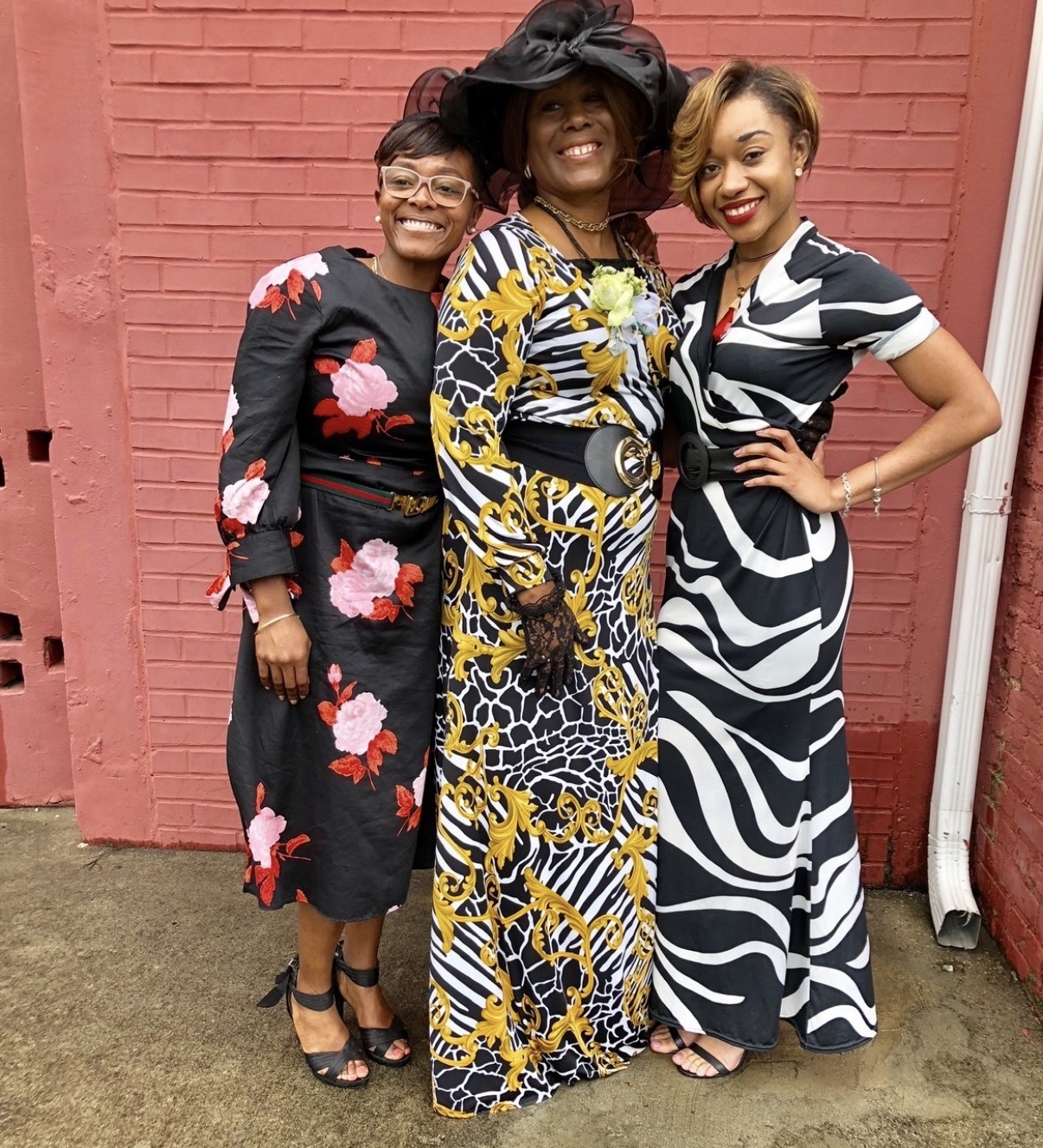 Mary in a black hat and zebra-print gown with her daughters in floral and zebra dresses